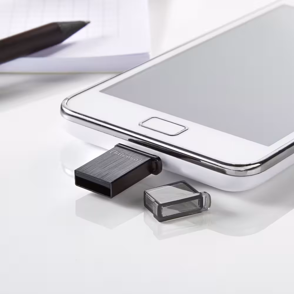 Intenso USB-sticks Mini Mobile Line 32GB: Compacte zwarte USB-stick met een transparante beschermkap, voor naast een smartphone.